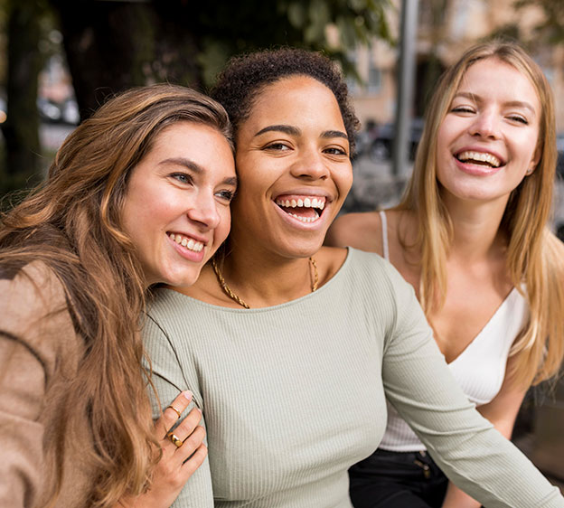 Photo of three young women smiling and embracing