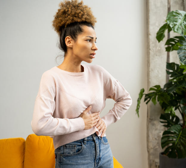 Young woman holds abdomen with hands and appears to be in pain or discomfort