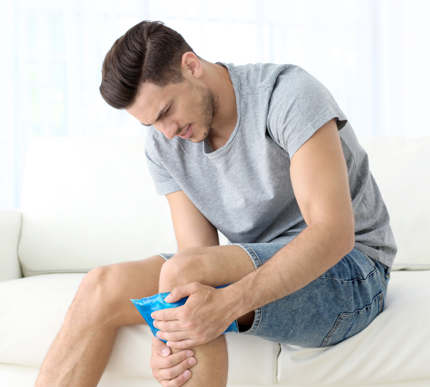 Young man applying cold compress to shin at home