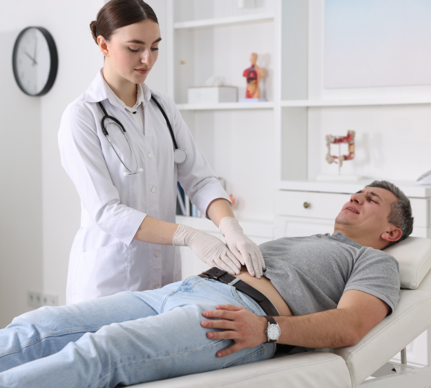Medical provider pressing on a patient’s abdomen while the patient is making a slightly grimaced face