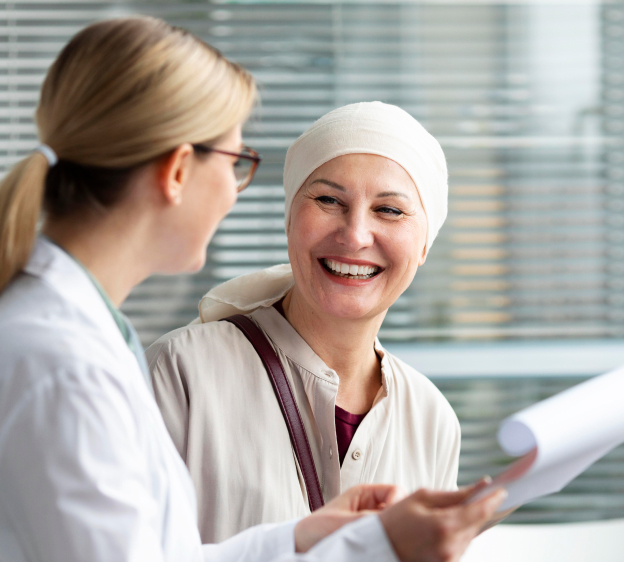 A smiling woman wearing a scalp cap looking toward a medical provider