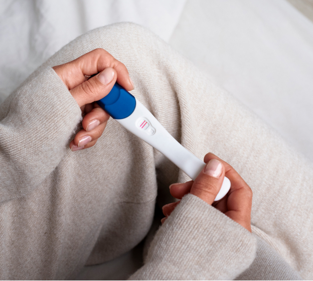 High angle view of a woman holding a positive pregnancy test with two red lines brightly displayed