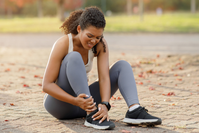 Female athlete experiencing an injured ankle after jogging outdoors