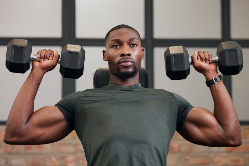 Black man lifting weights, holding two smaller weights in each hand, lifting the weights upward