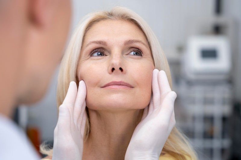 Close-up of a medical provider touching a woman’s cheeks and the sides of her face with his fingertips
