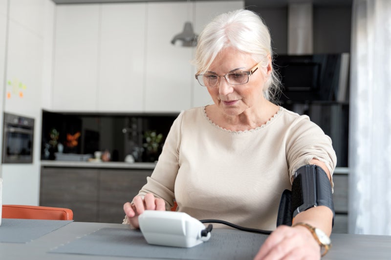 Older adult woman checking blood pressure at home