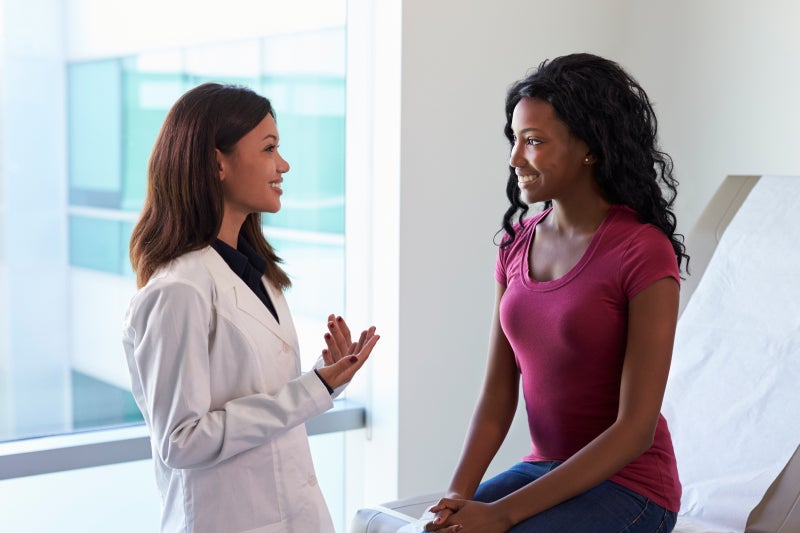 Female doctor meeting with patient in exam room