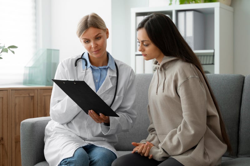 A doctor and patient review a medical chart together in a bright clinic, conveying attentive care, consultation and reassurance