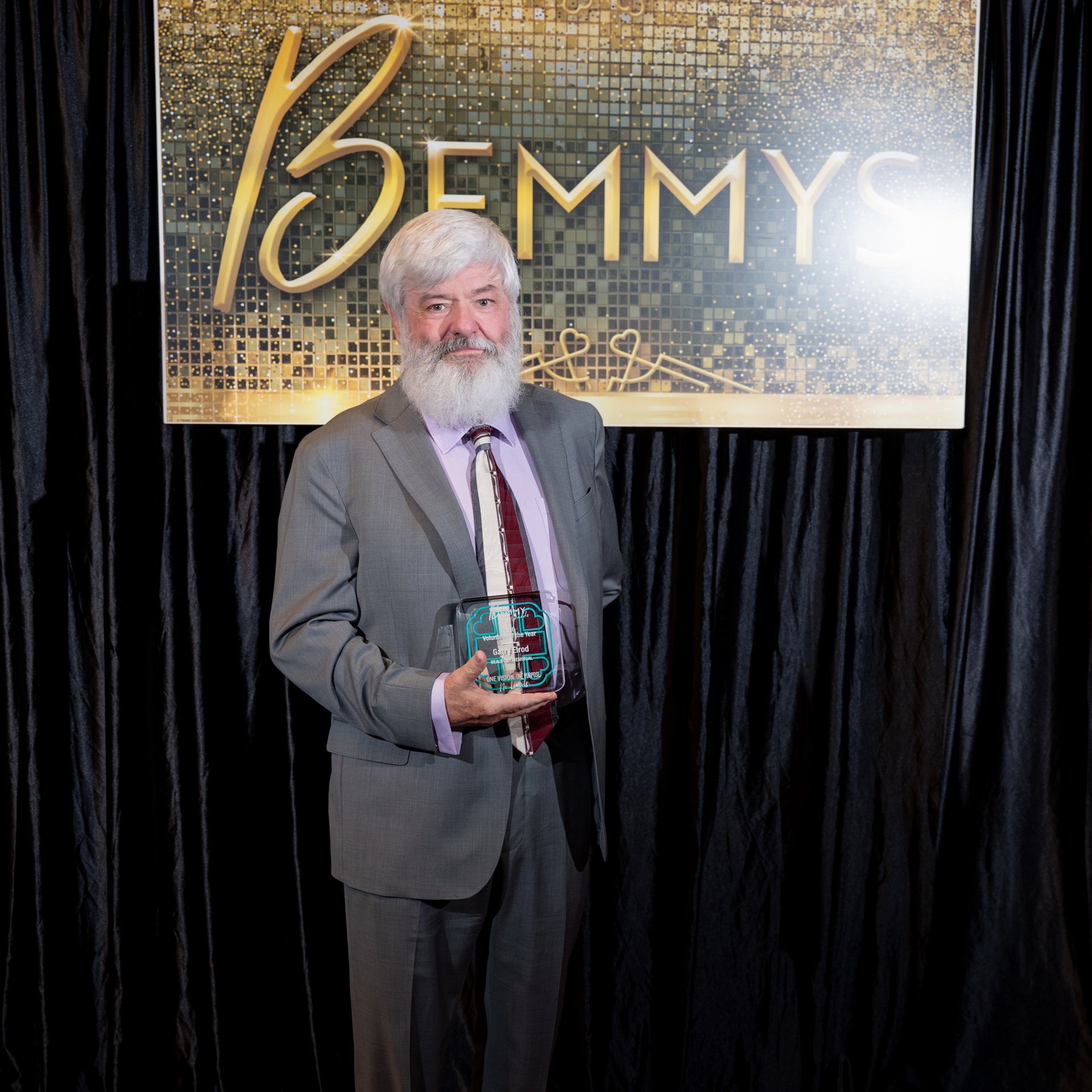 Garry Elrod holds a 2026 Bemmy Award in front of a black backdrop and hanging sign that reads BEMMYS.