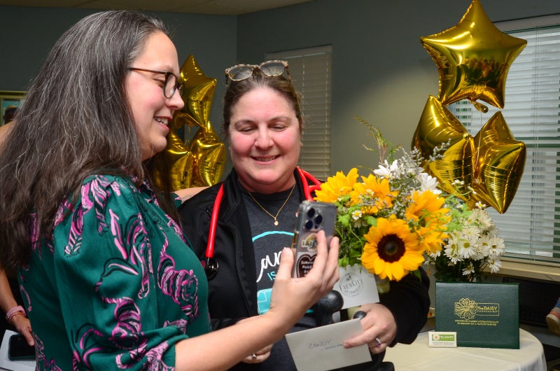 Angie Boswell and Candy Chappell look at a phone that Angie holds in her right hand.