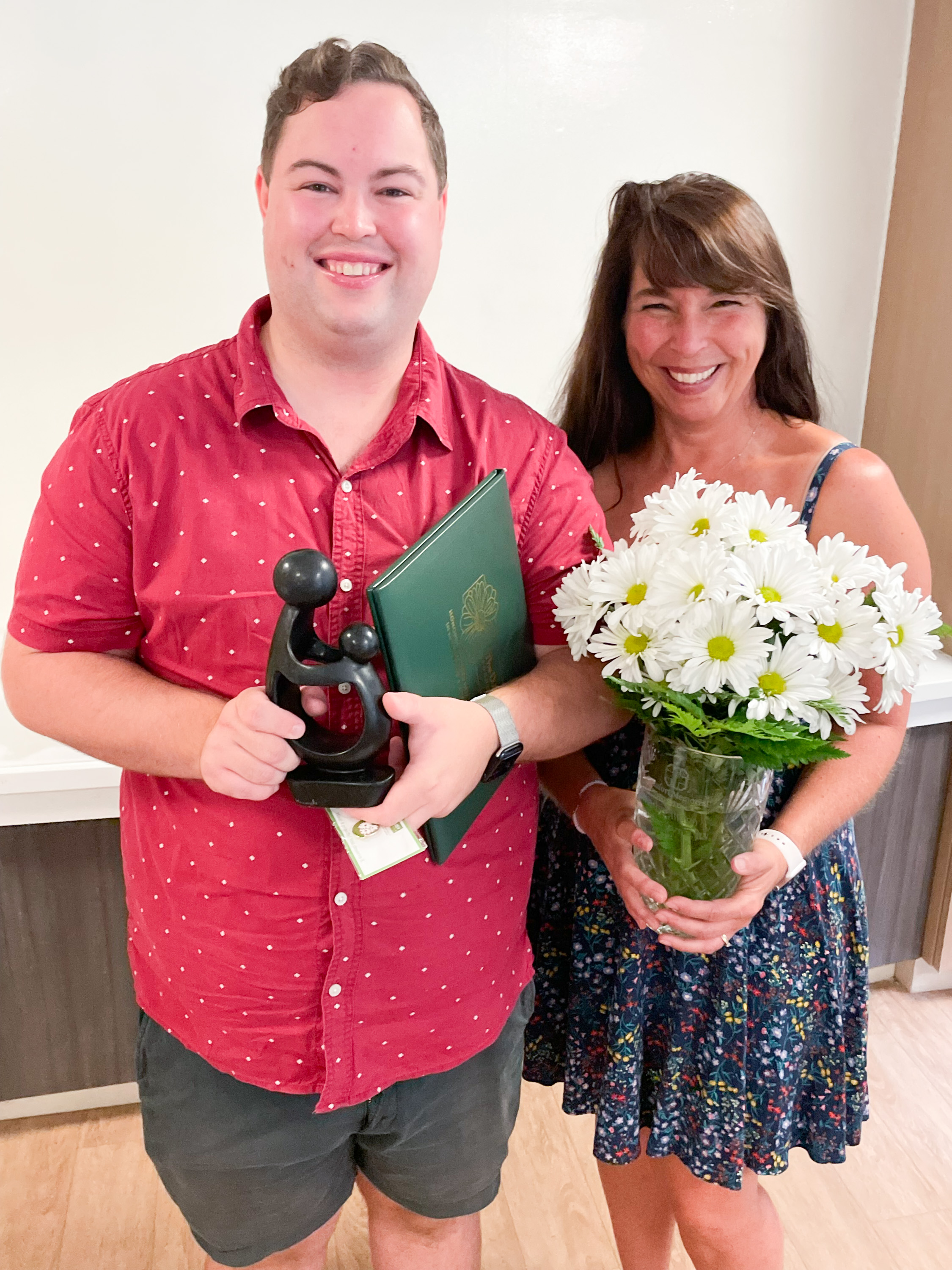 Jonathan Barrett, RN, BSN, holds his DAISY Award standing next to his mother Pam