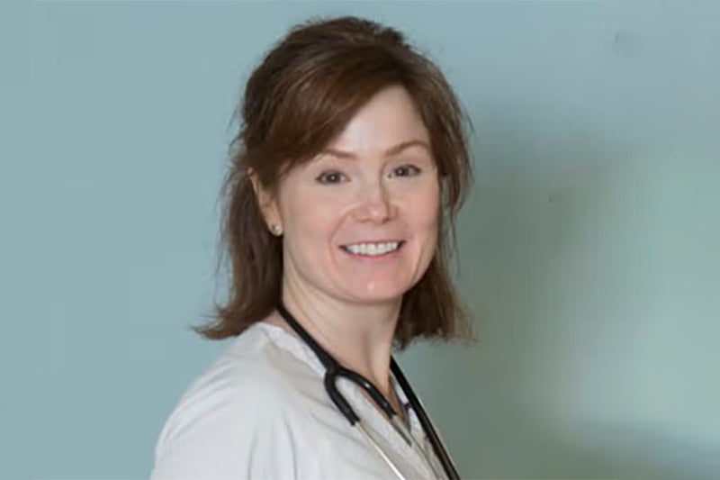 Marcellene Trask stands in front of a light blue colored wall wearing a stethoscope around her neck