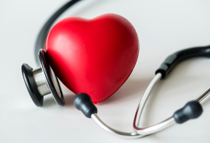 A stethoscope is wrapped lightly around a red heart-shaped object.