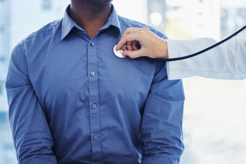 Doctor patient and consultation with stethoscope on heart in hospital for healthcare or health insurance black man and cardiology person check lungs breathing and wellness of body and organ.