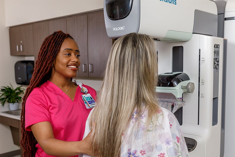 A Beaufort Memorial mammography technician smiles at a patient as she stands in front of the mammography machine