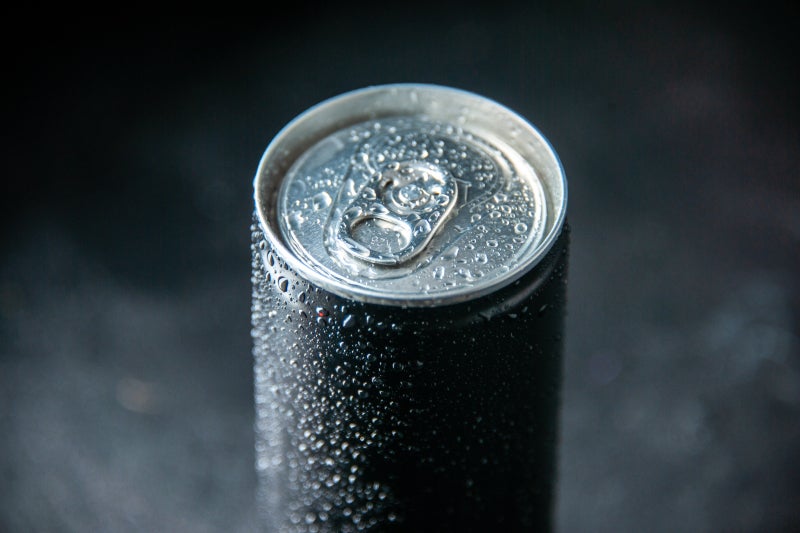 A dark aluminum beverage can with some condensation on the top and along the sides.