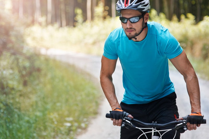 Middle age man riding a bicycle down a trail on a sunny day