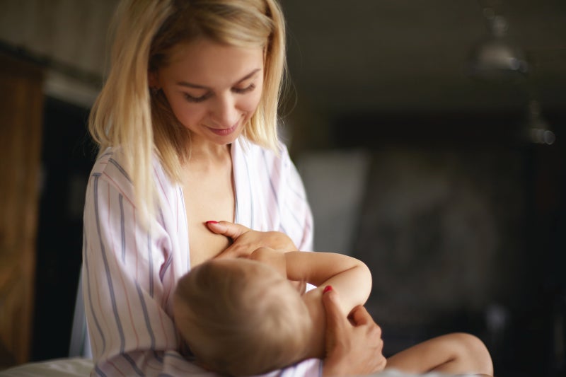 Mother with blonde hair breastfeeding her infant child.