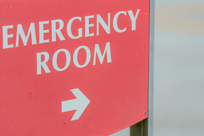 Red sign with white lettering spelling out Emergency Room and a white arrow pointing to the right.