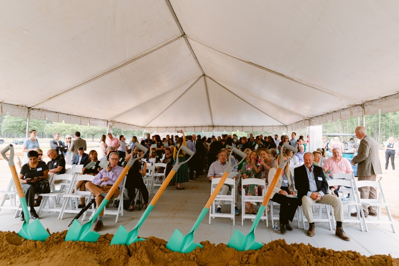 A view of the groundbreaking ceremony attendees from the podium with the dirt box and shovels in the foreground