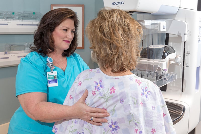 A Breast Health Center employee supports a woman getting a mammogram.