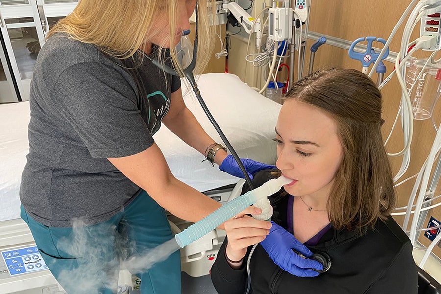 A respiratory therapist helps a patient using a nebulizer.