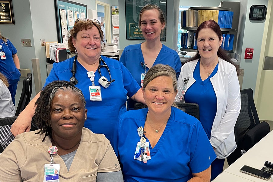 A group of healthcare employees at Beaufort Memorial pose for a photo at a desk.