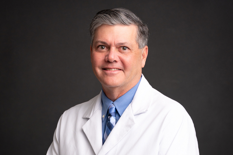 Professional headshot of Terry Grainger, MD, FACC wearing a white lab coat