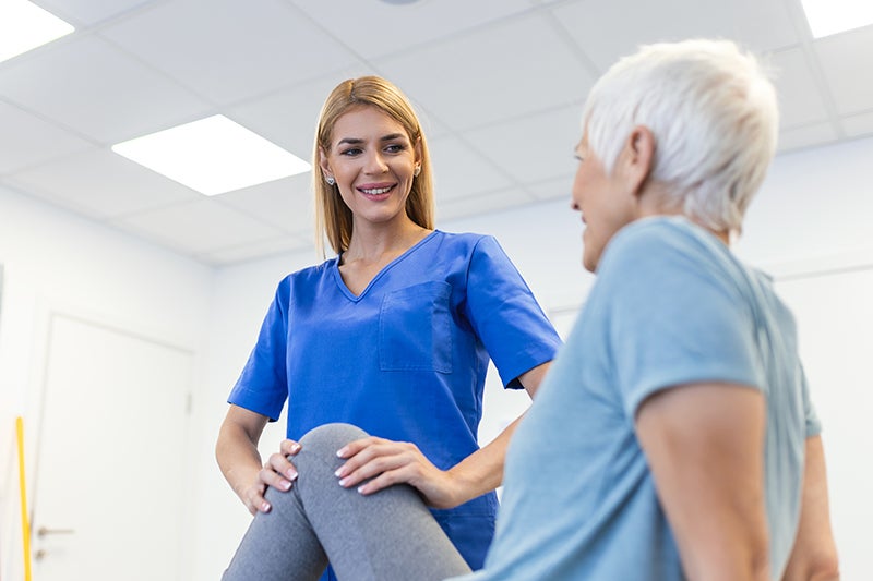 Female physiotherapist working on the knee of a seated elderly female.