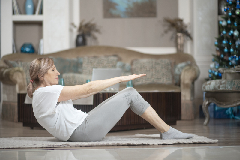 middle age woman sits on floor doing exercises
