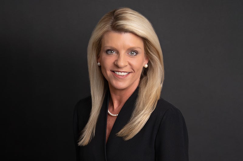 Professional headshot of Courtney Smith in front of a dark grey backdrop.