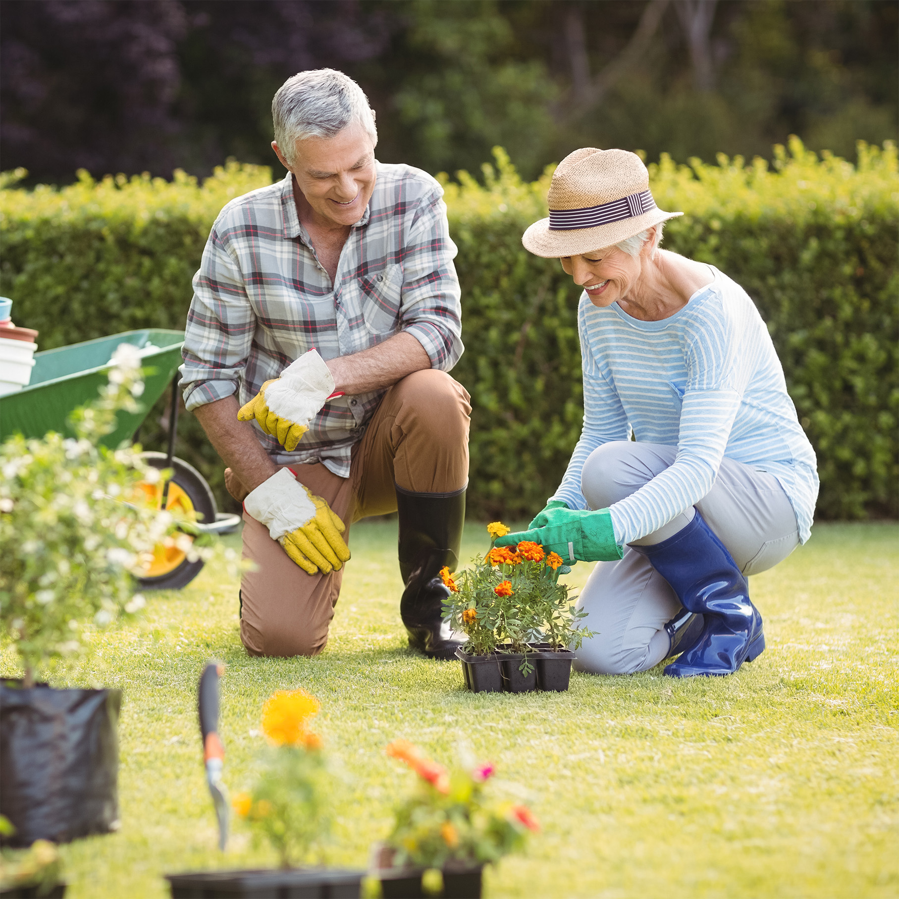 A couple smiling and kneeling in the grass performing gardening tasks. Register for a Beaufort Memorial Joint Pain Seminar