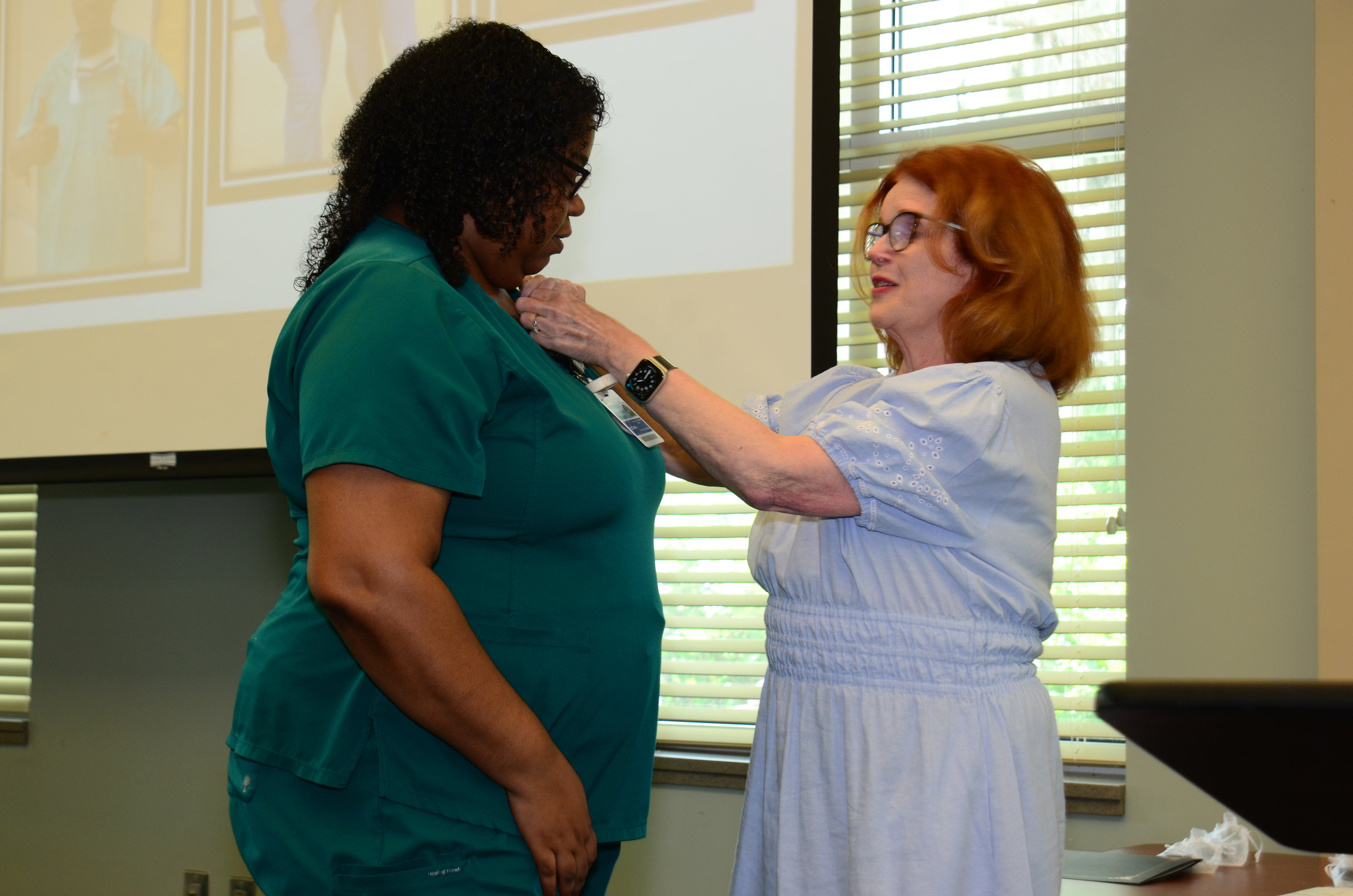 Edwina Register, CCMA receives her national certification pin from MaryAnn McNamara.