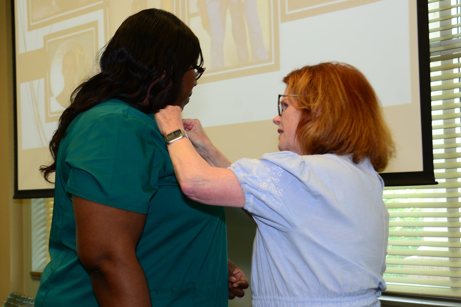 Tonya Coaxum, CCMA receives her national certification pin from MaryAnn McNamara