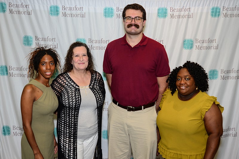 Graduates of Beaufort Memorial's PATH Program cohort 13 pose for a photo in front of a white step and repeat backdrop.