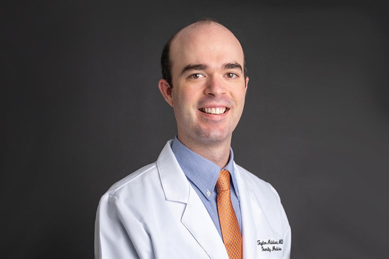 Dr. Taylor Addison, a family medicine physician at Beaufort Memorial Lowcountry Medical Group Primary Care, in a white lab coat in front of a dark backdrop.