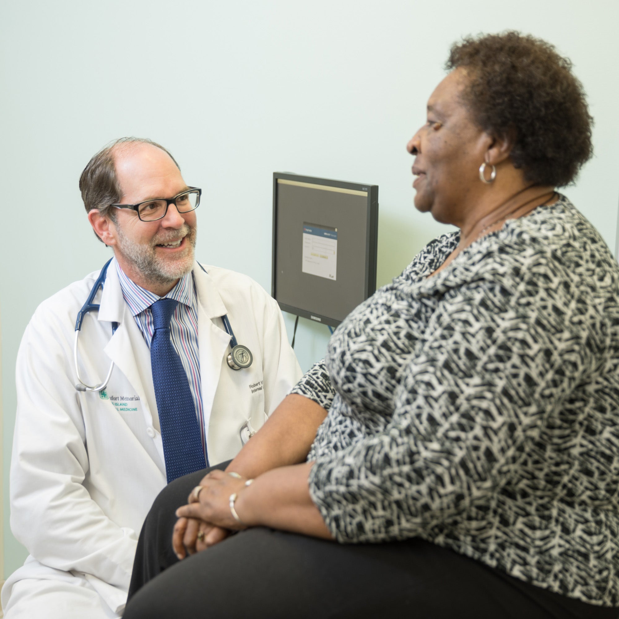 Need a Primary Care Provider belly band image of Dr. Vyge and a patient in a clinical setting.
