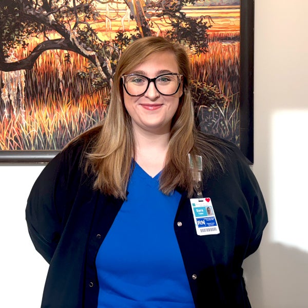 Sarah Tuten, a registered nurse at Beaufort Memorial, stands in front of a framed Lowcountry marsh photo on a wall.