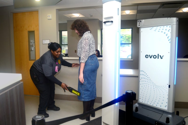 A female security officer scans a woman just past the weapons detection system at the entrance to the Pratt Emergency Center as part of enhanced security measures.