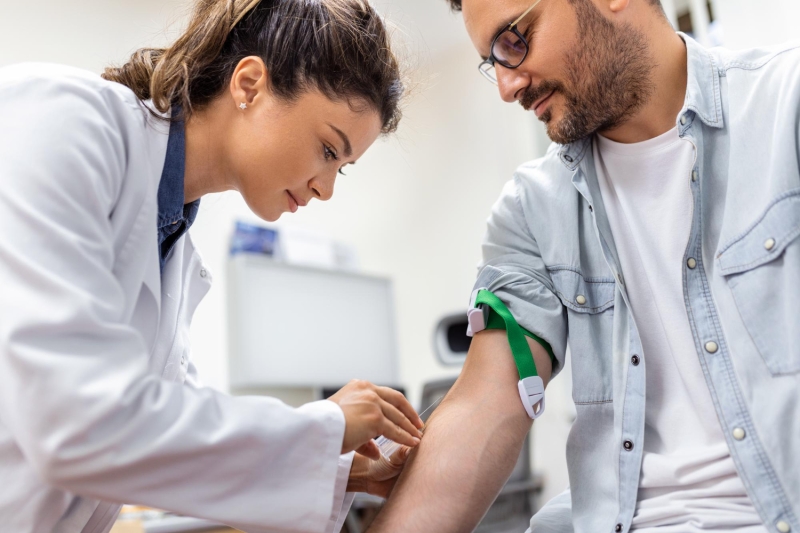 Female healthcare provider prepares to draw blood from a male patient