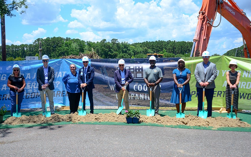 A group of representatives from project partners for the LiveWell Terrace affordable housing project stand behind a small dirt pile, each with shovels for the groundbreaking ceremony.