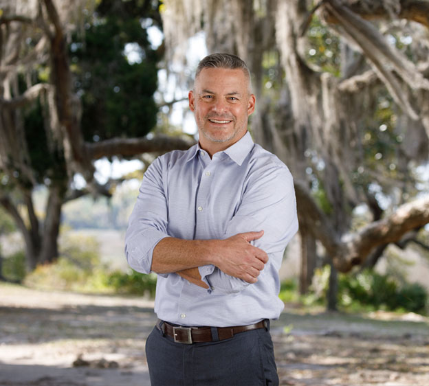 Dr. Robert Smith, Beaufort Memorial primary care provider, stands in front of a live oak tree, smiling with his arms crossed.