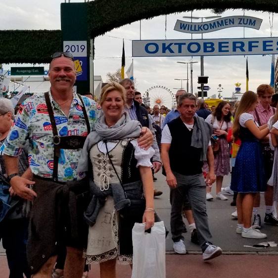John Aust standing with his wife Kim with an Oktoberfest sign behind them