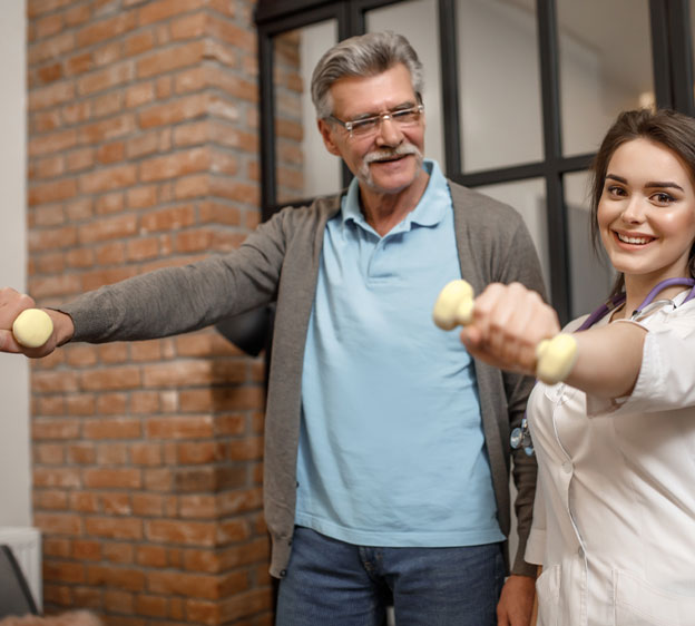 An adult man works with a female therapist. He holds small weights in each hand and has his arms extended straight in front of him.