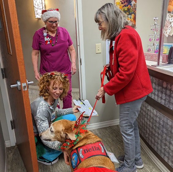 Sunday Brown holds Bella's leash while two Beaufort Memorial staff members, one wearing a Santa hat, say hello