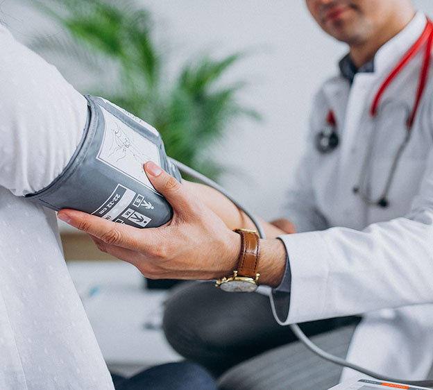 A patient wears a blood pressure cuff as a health care provider measures their blood pressure.