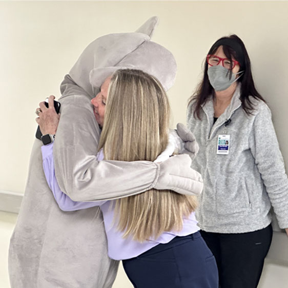Lisa Calasant, PT, hugs Banjo the mascot during visit