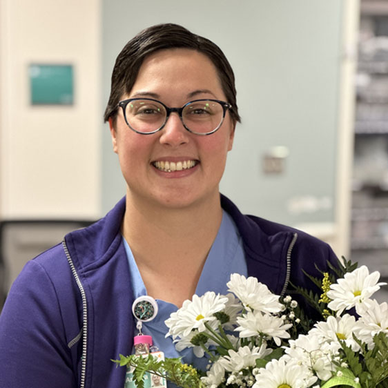 Andrea Farr, RN, smiles while holding a bouquet of daisies