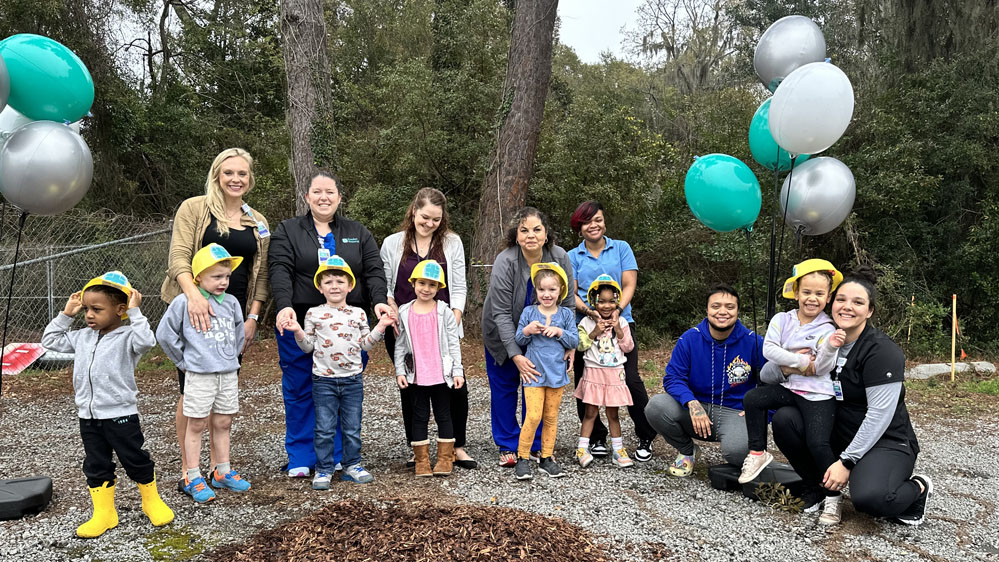 Parents and their children smile at the site where a new childcare development center will be built 