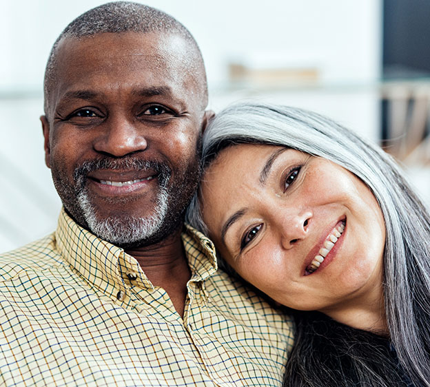 A middle-age African American man sits with his wife. Both smile at the camera.